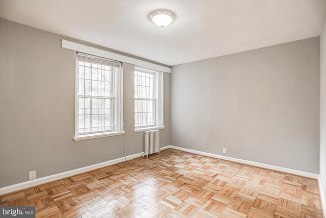 unfurnished room featuring radiator heating unit and light parquet floors