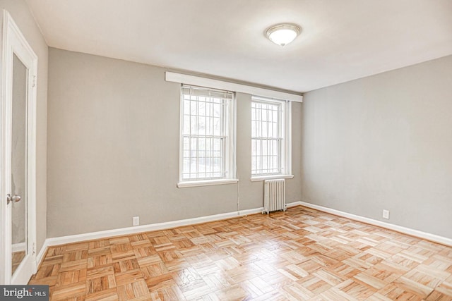 empty room with radiator heating unit and light parquet flooring