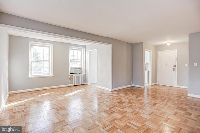 empty room with light parquet flooring, radiator, and cooling unit