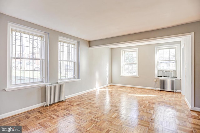 empty room featuring radiator heating unit and light parquet floors