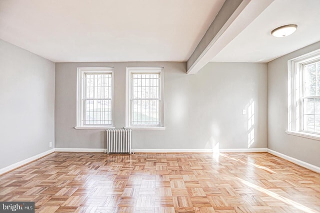 empty room with light parquet flooring and radiator