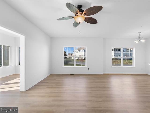 unfurnished living room with a wealth of natural light, light hardwood / wood-style flooring, and ceiling fan with notable chandelier