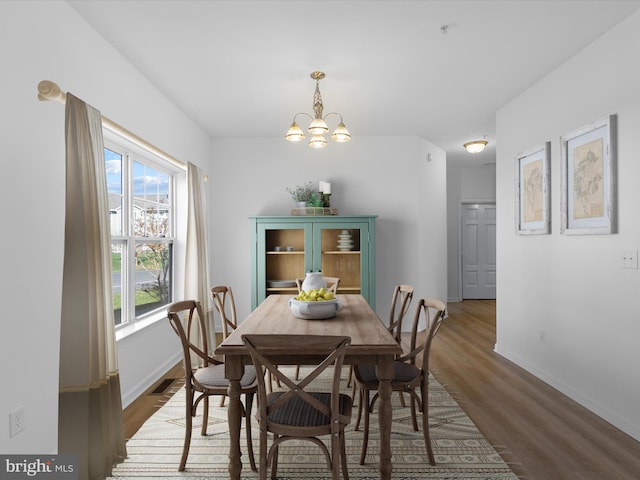 dining space with dark hardwood / wood-style flooring, plenty of natural light, and a notable chandelier