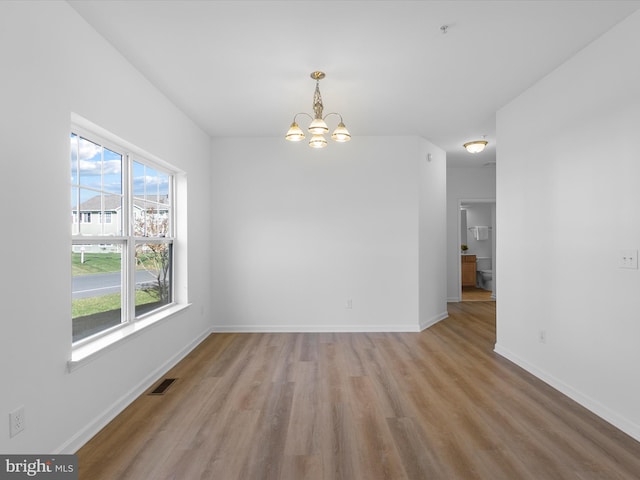 unfurnished dining area with light hardwood / wood-style flooring, an inviting chandelier, and a healthy amount of sunlight