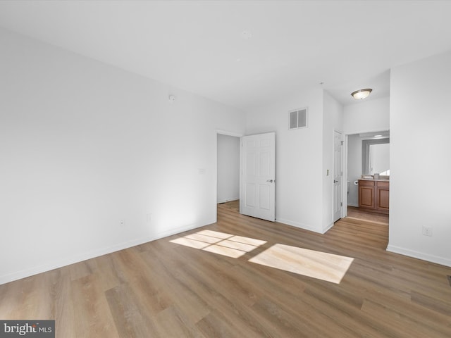 unfurnished bedroom with ensuite bath and light hardwood / wood-style flooring