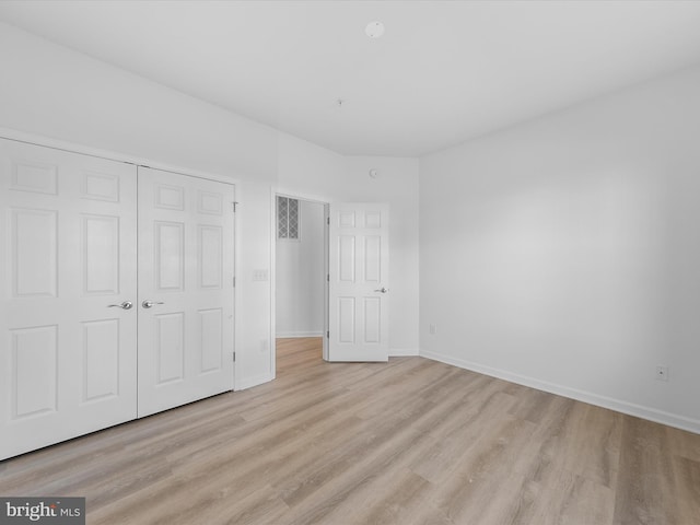 unfurnished bedroom with light wood-type flooring and a closet