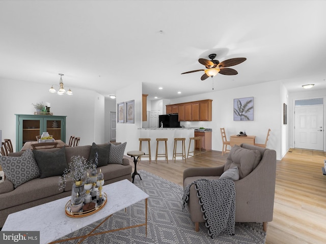 living room featuring ceiling fan with notable chandelier and light hardwood / wood-style floors