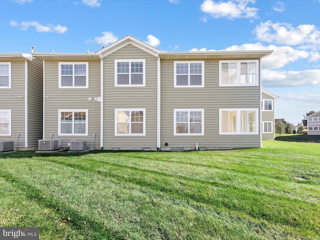 rear view of property with central AC unit and a yard