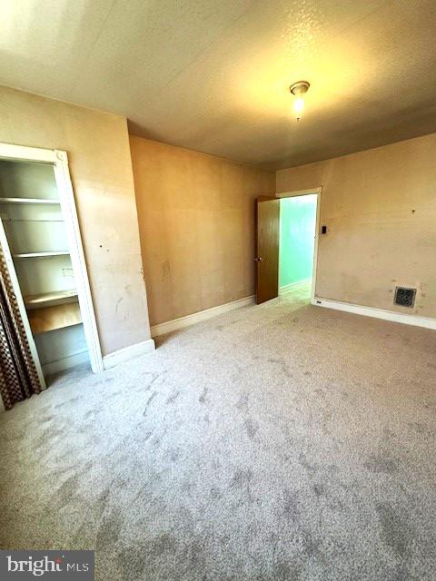 carpeted empty room with a textured ceiling