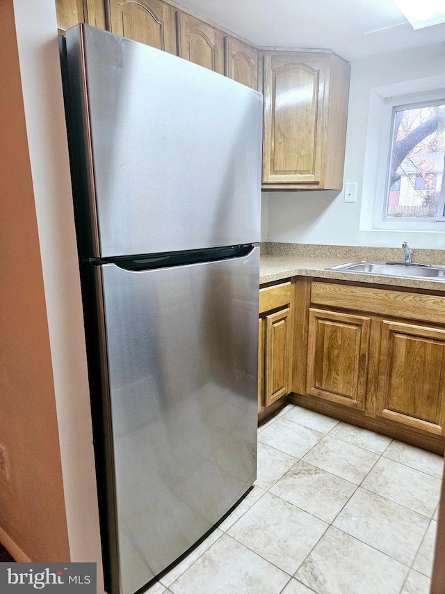 kitchen featuring stainless steel fridge, sink, and light tile patterned floors