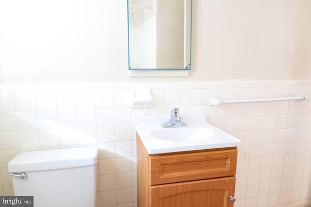 bathroom with vanity, toilet, and tile walls