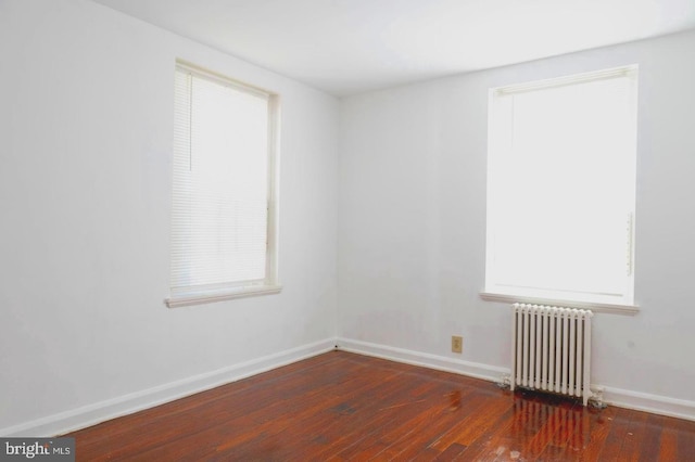 empty room with radiator heating unit and dark hardwood / wood-style floors