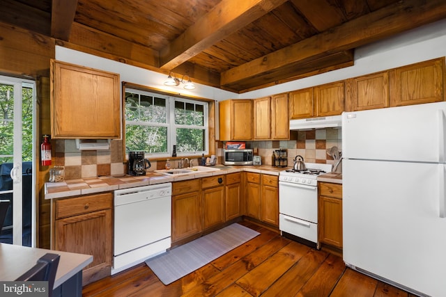 kitchen with a healthy amount of sunlight, white appliances, dark wood-type flooring, and tasteful backsplash