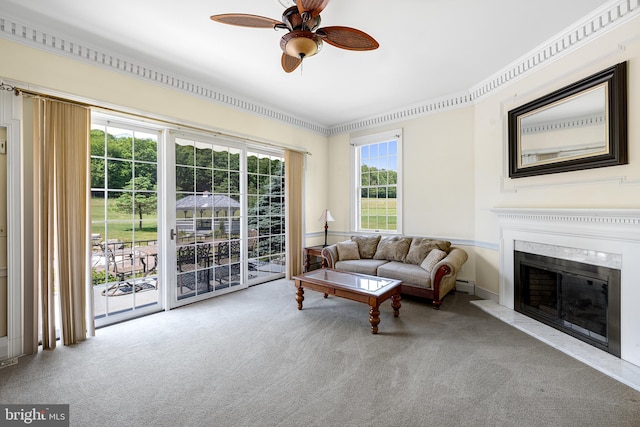 carpeted living room with ceiling fan, a fireplace, and crown molding