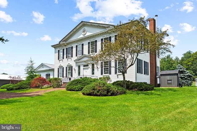 view of front of house with a front yard and a shed