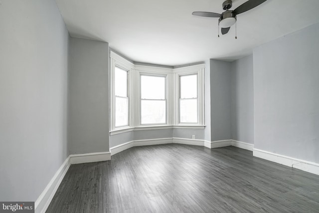 empty room with ceiling fan and dark hardwood / wood-style flooring