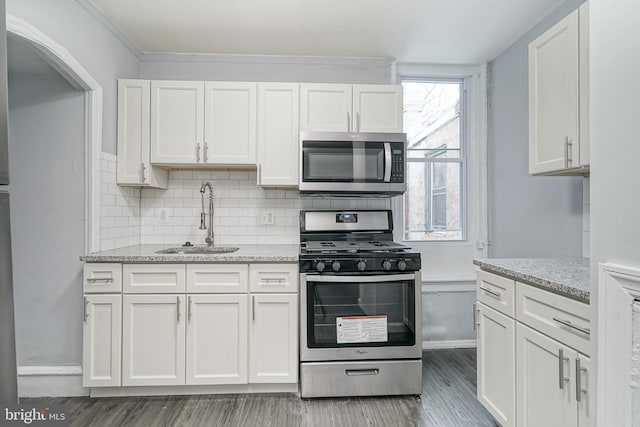 kitchen featuring white cabinetry, sink, stainless steel appliances, and wood-type flooring