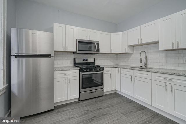 kitchen featuring white cabinets, backsplash, sink, and stainless steel appliances