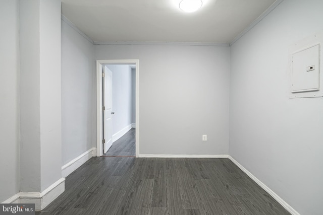 empty room featuring dark hardwood / wood-style floors, crown molding, and electric panel