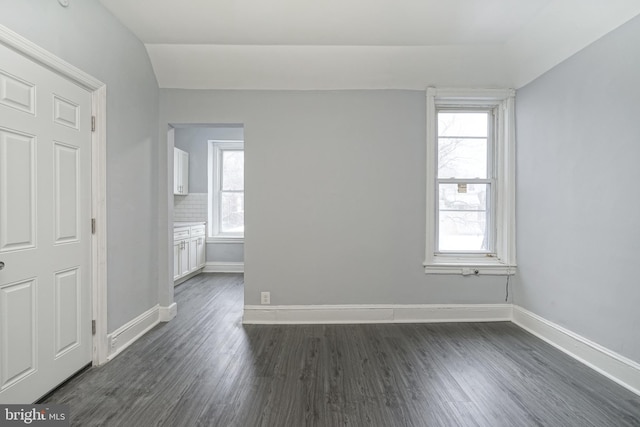 unfurnished room with lofted ceiling and dark wood-type flooring