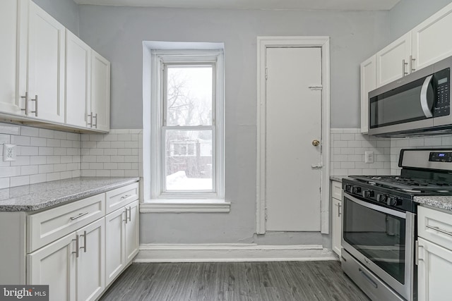 kitchen featuring white cabinetry, light stone counters, dark hardwood / wood-style floors, decorative backsplash, and appliances with stainless steel finishes