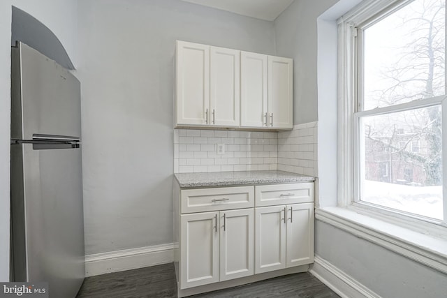 kitchen featuring tasteful backsplash, stainless steel fridge, plenty of natural light, and white cabinets