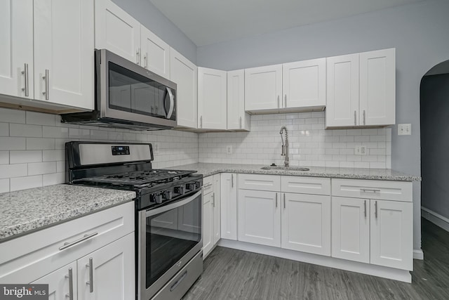 kitchen featuring sink, stainless steel appliances, tasteful backsplash, dark hardwood / wood-style floors, and white cabinets