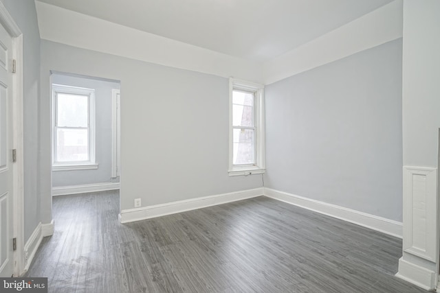 unfurnished room featuring dark wood-type flooring and a wealth of natural light