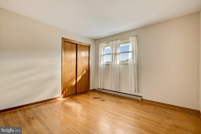 unfurnished bedroom with a closet, light hardwood / wood-style flooring, and a baseboard radiator