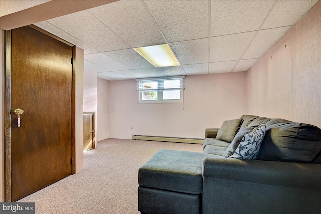 carpeted living room with a drop ceiling and a baseboard heating unit