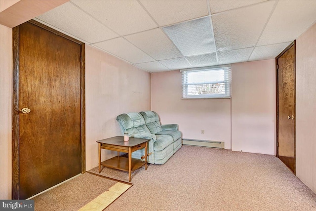 living area featuring baseboard heating, a paneled ceiling, and light colored carpet