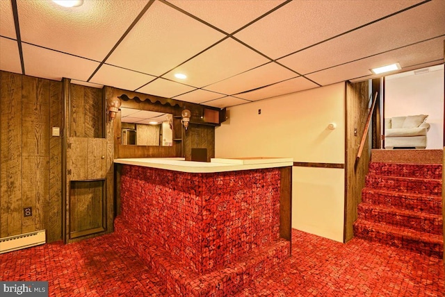 bar featuring a drop ceiling, wood walls, and a baseboard radiator