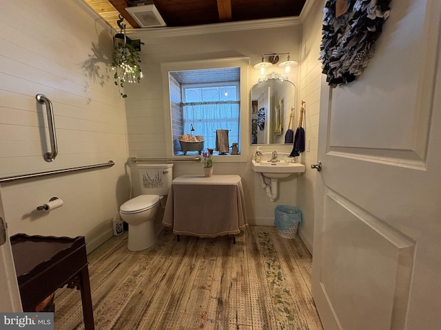 bathroom with hardwood / wood-style flooring, toilet, and crown molding