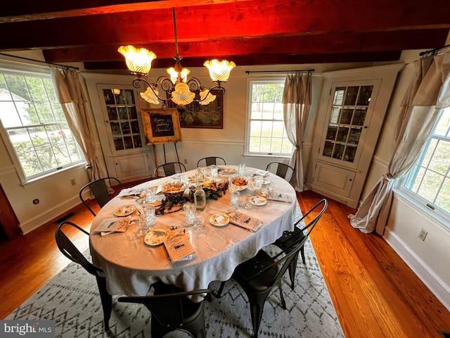 dining area with hardwood / wood-style floors, a notable chandelier, and beam ceiling