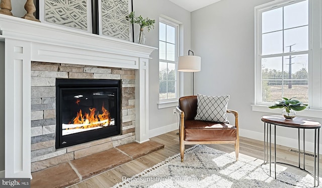 sitting room featuring a fireplace, wood-type flooring, and a wealth of natural light