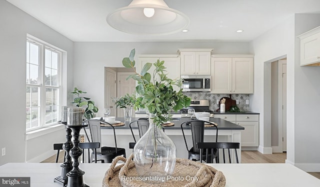 kitchen with light wood-type flooring, white cabinetry, appliances with stainless steel finishes, and tasteful backsplash