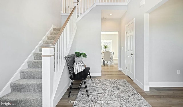 stairway with hardwood / wood-style floors and a towering ceiling