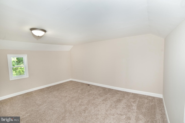 additional living space with light carpet and vaulted ceiling