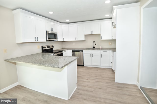 kitchen featuring kitchen peninsula, stainless steel appliances, light hardwood / wood-style floors, and sink