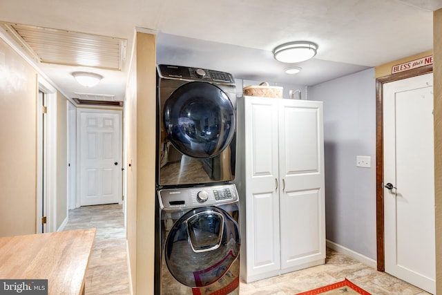 washroom featuring cabinets and stacked washer / dryer