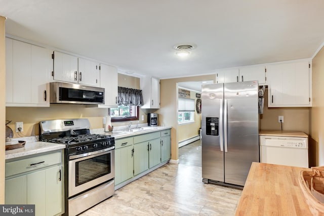 kitchen featuring sink, green cabinetry, appliances with stainless steel finishes, a baseboard radiator, and white cabinetry