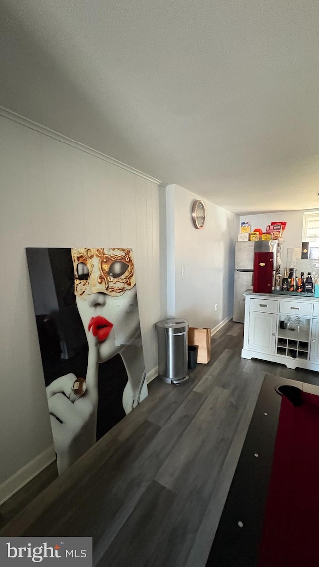 interior space featuring baseboards, a dry bar, and dark wood-style flooring