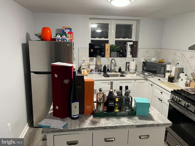 kitchen with sink, tasteful backsplash, dark hardwood / wood-style floors, white cabinets, and appliances with stainless steel finishes