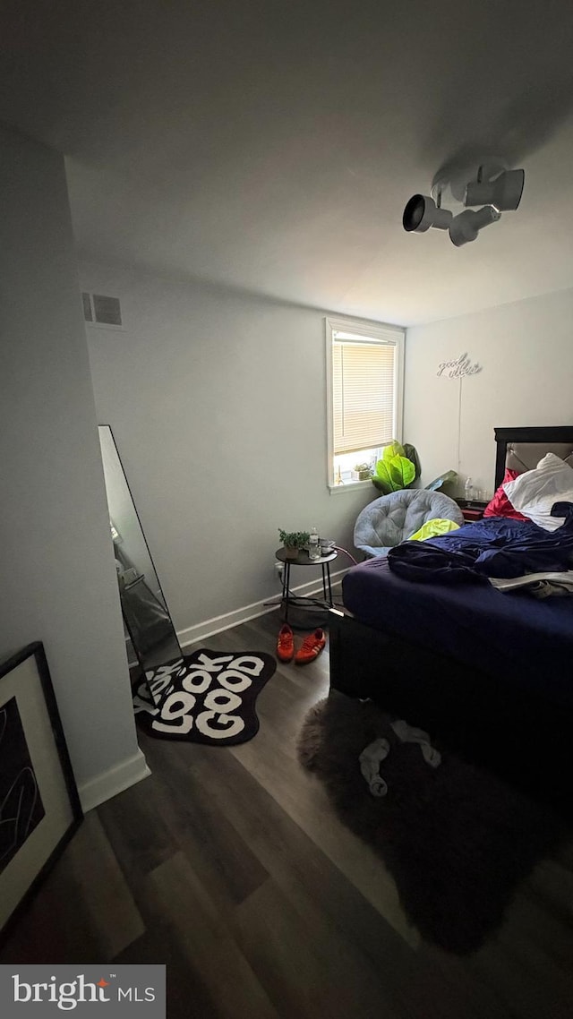 bedroom featuring visible vents, baseboards, and wood finished floors