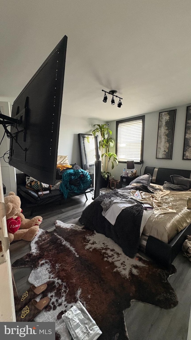 bedroom with track lighting and wood finished floors