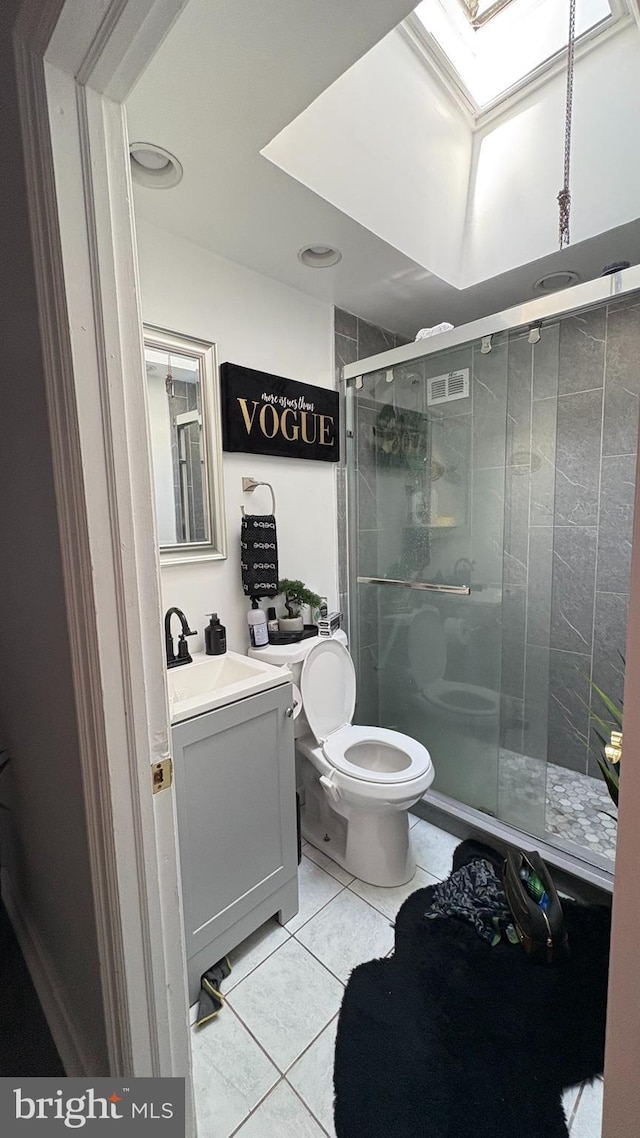 full bathroom with tile patterned flooring, vanity, toilet, a shower stall, and a skylight