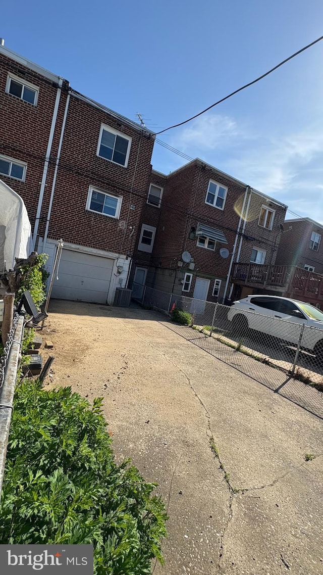 view of front facade featuring fence, central air condition unit, an attached garage, and driveway