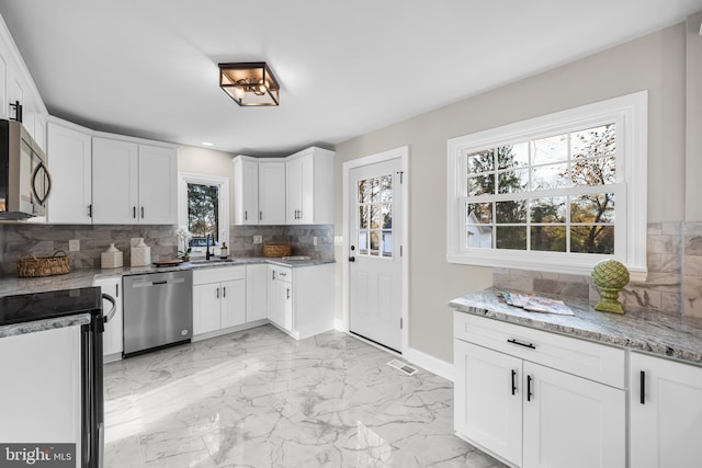 kitchen with stainless steel appliances, white cabinetry, and a healthy amount of sunlight