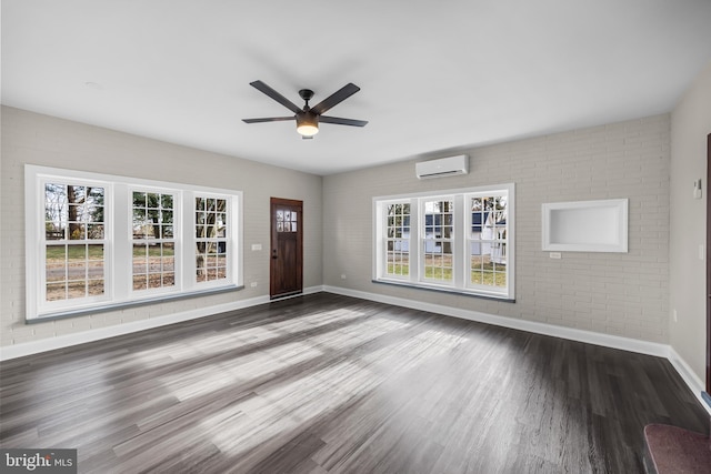 unfurnished living room featuring a wall mounted AC, ceiling fan, brick wall, and dark hardwood / wood-style floors