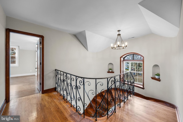 stairway featuring a chandelier, hardwood / wood-style floors, a healthy amount of sunlight, and lofted ceiling